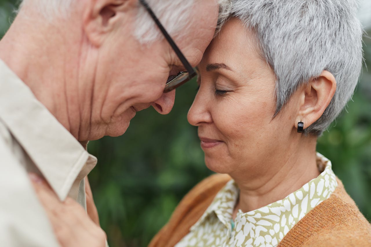 A tender moment between a senior couple, expressing love and affection outdoors.