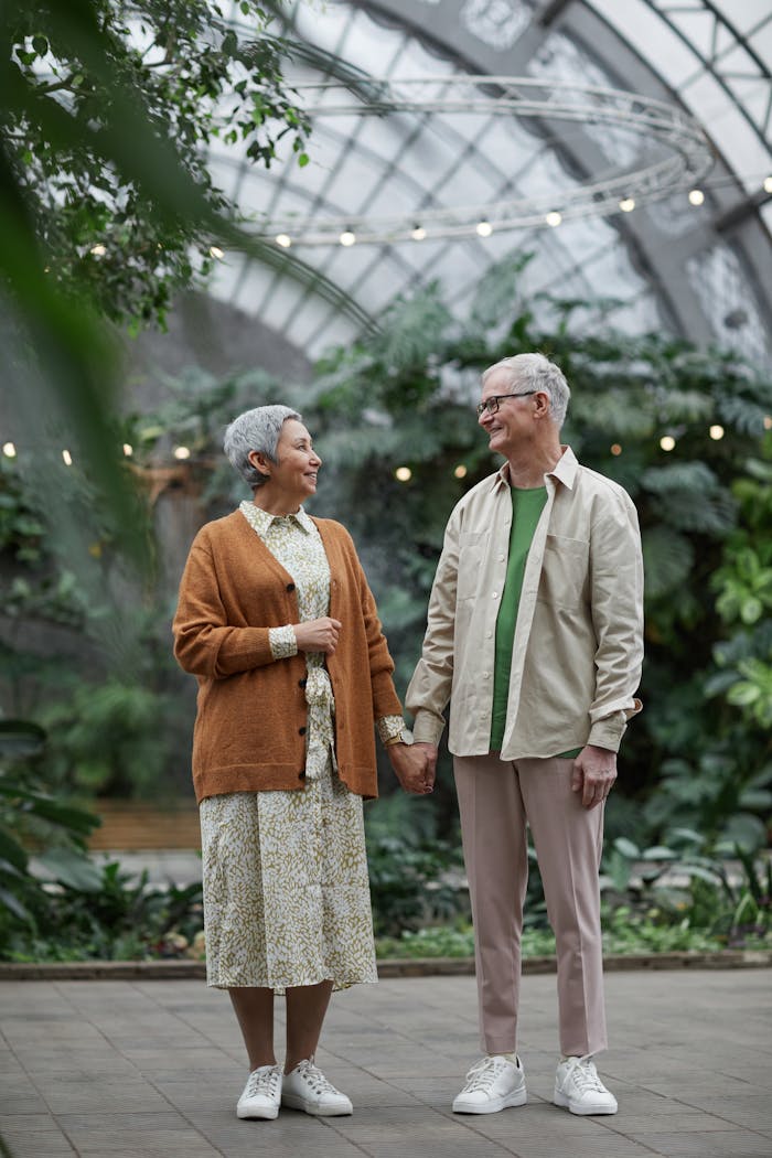 Elderly couple enjoying a romantic moment together in a lush indoor greenhouse.
